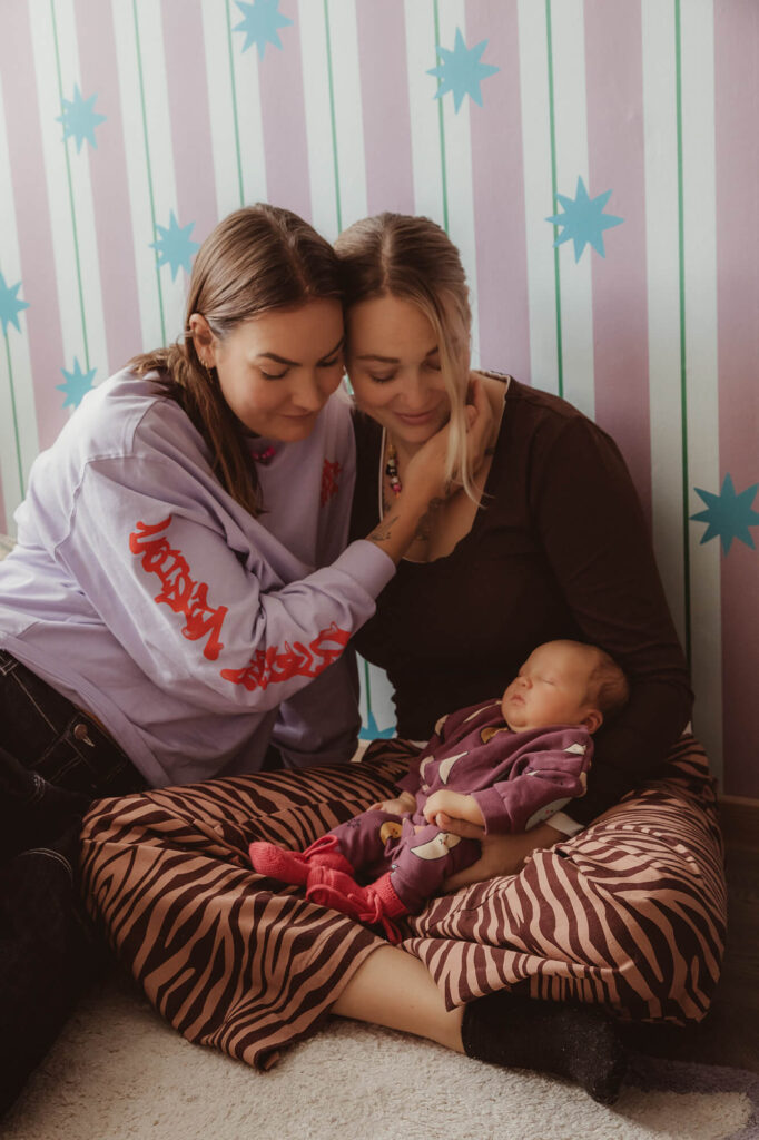 Ouders in kleurrijke eigen kleding knuffelen met hun baby voor behang met roze strepen en sterren